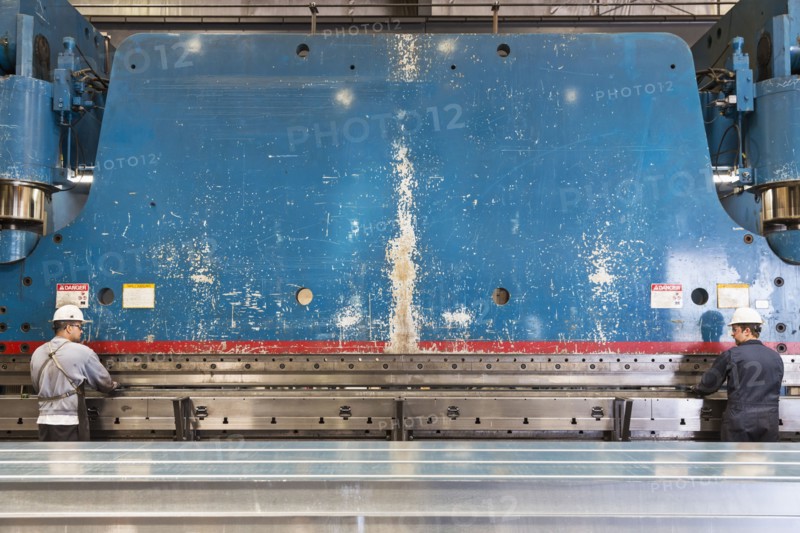 Workers fabricating metal in factory