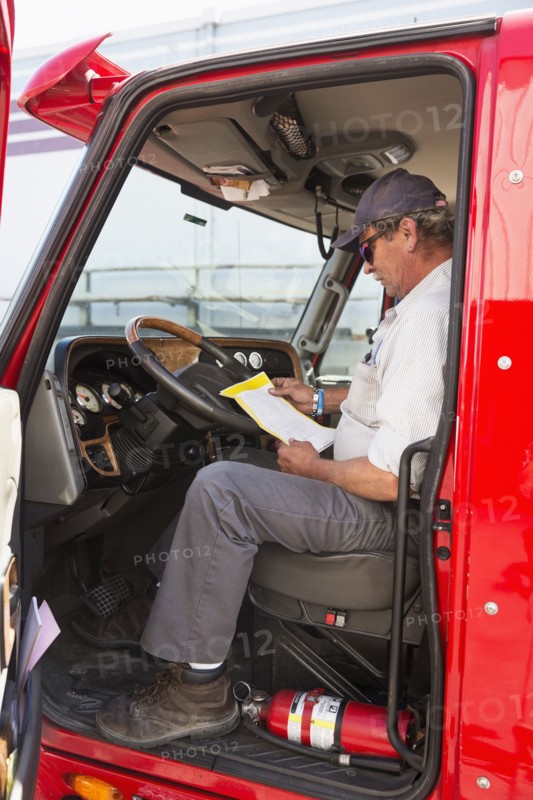 Caucasian semi-truck driver reading paperwork