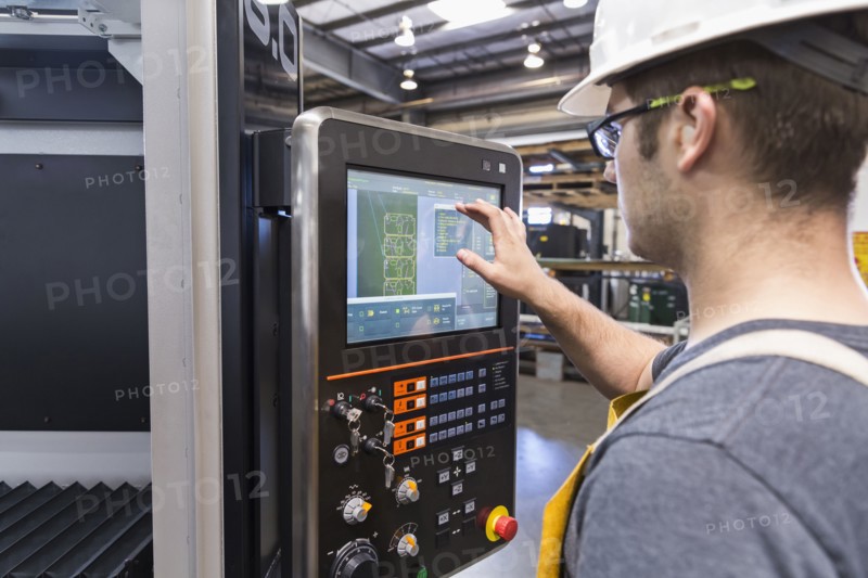 Caucasian worker using control panel in factory