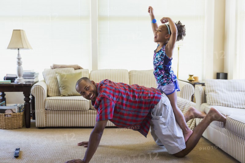 Mixed race father and daughter playing on floor in livingroom