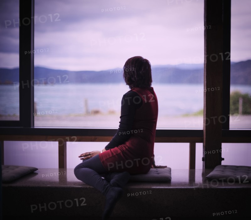 Mixed race woman looking out window of modern house