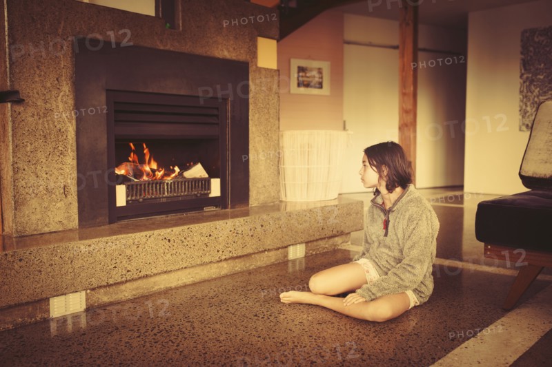 Mixed race girl relaxing by fireplace in living room