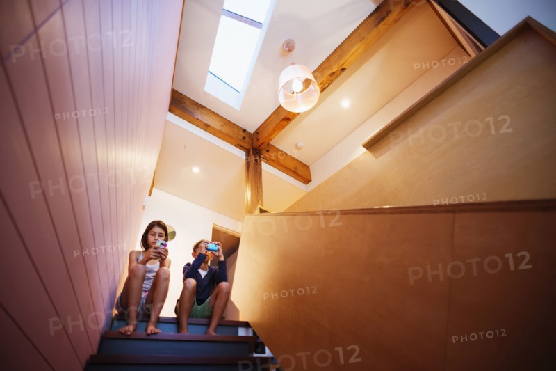Mixed race children using cell phones on staircase