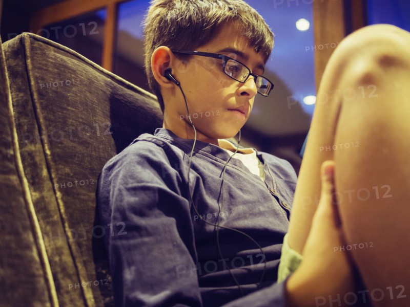 Mixed race boy listening to earbuds on sofa