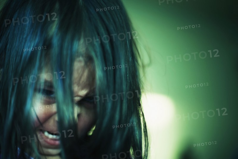 Angry mixed race girl peering up through hair