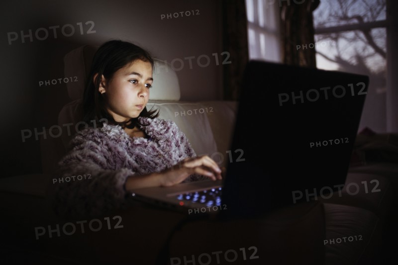 Mixed race girl using laptop at night