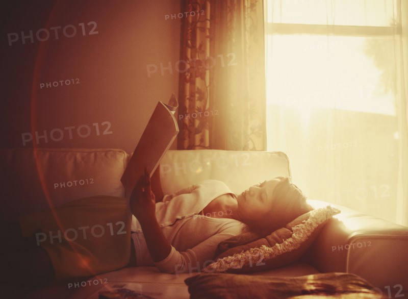 Mixed race woman using digital tablet on living room sofa