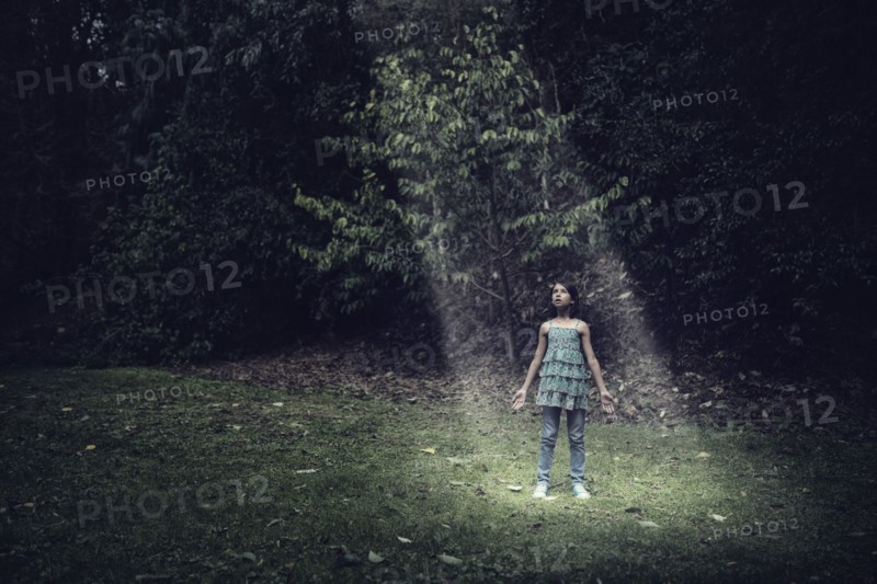 Mixed race girl standing in beam of light outdoors