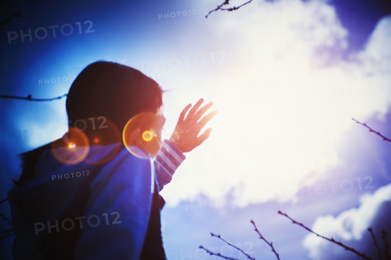 Mixed race girl shielding herself from sun lens flare