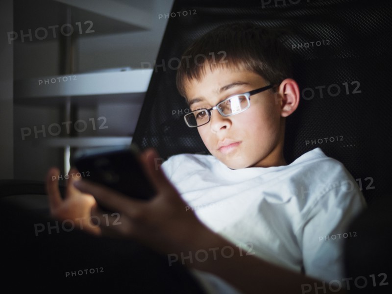 Mixed race boy texting on cell phone at night