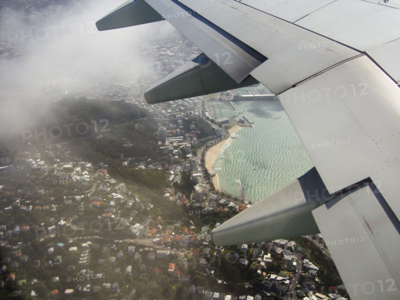 Aerial view of airplane wing flying over Wellington cityscape