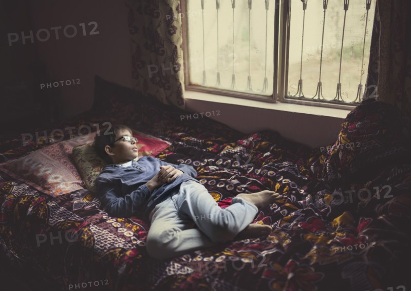 Mixed race boy looking out bedroom window