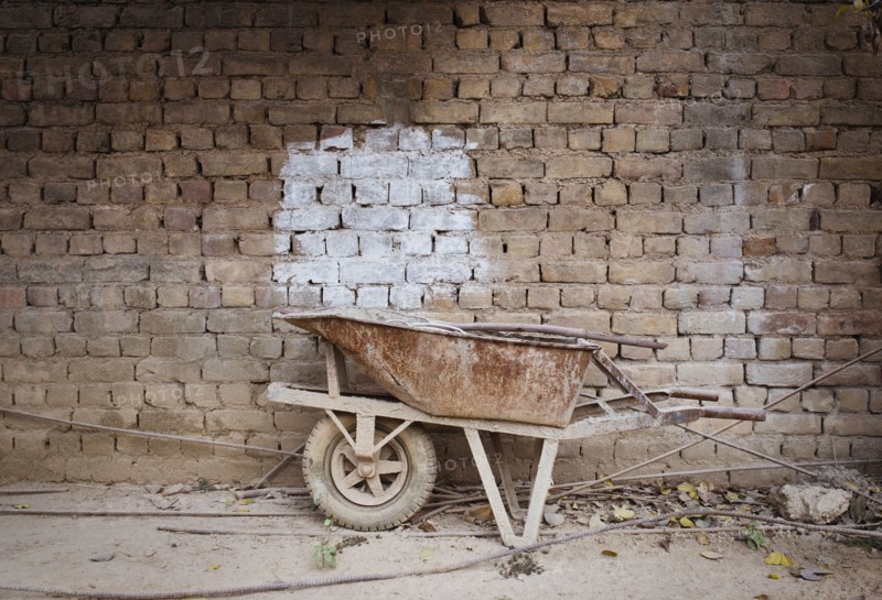 Empty wheelbarrow near brick wall