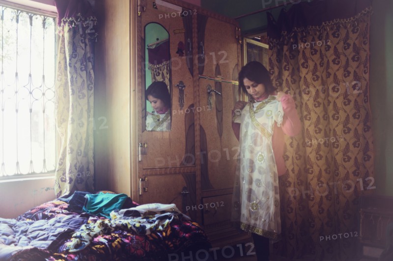 Mixed race woman examining dress in bedroom