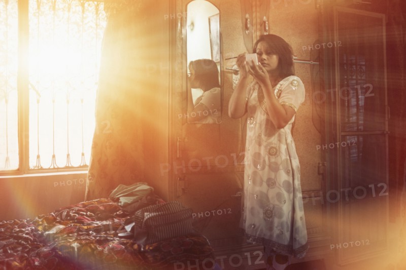Mixed race woman applying makeup in bedroom