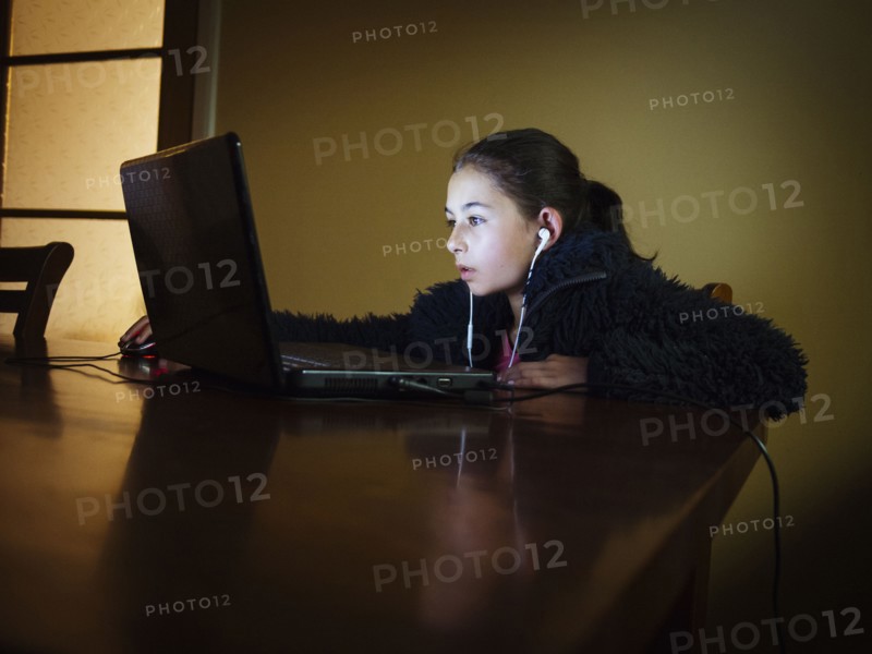 Mixed race girl using laptop at table night