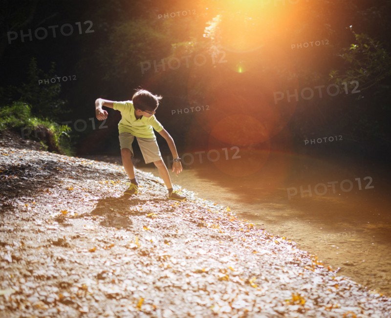 Mixed race boy skipping stones in stream