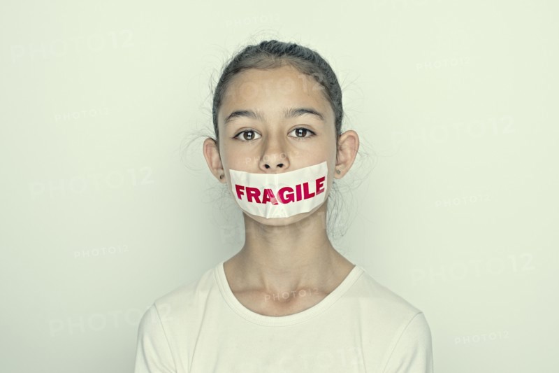 Mixed race girl wearing fragile sticker over mouth