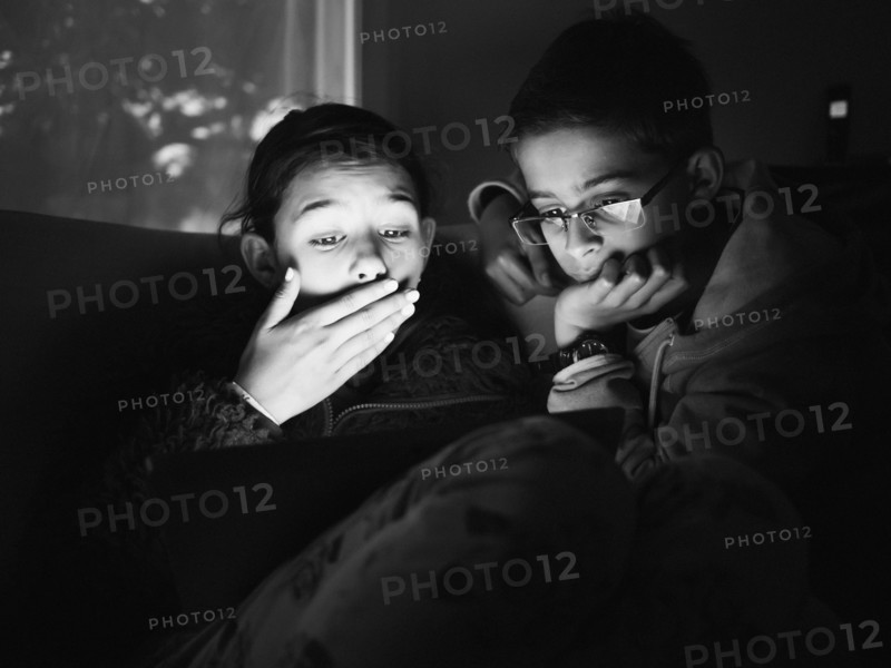 Mixed race children using digital tablet at night