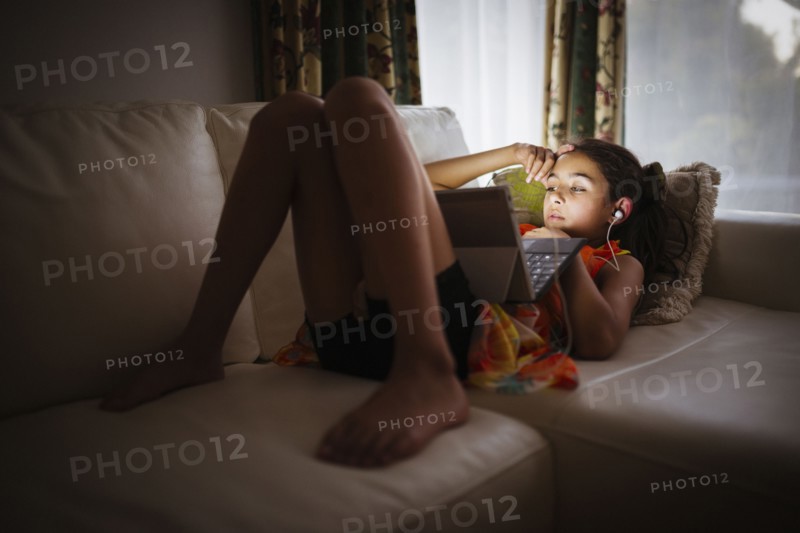 Mixed race girl using digital tablet on sofa