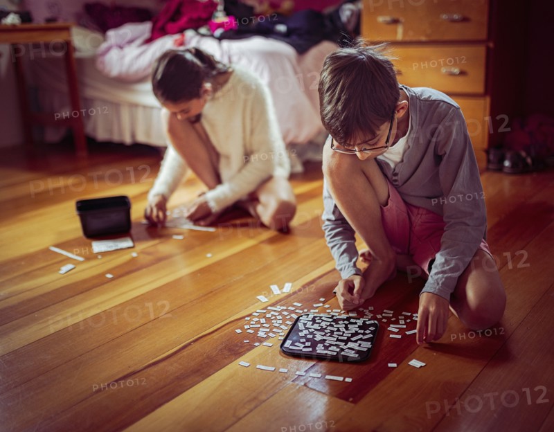 Mixed race children doing puzzles on bedroom floor