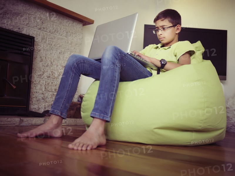 Mixed race boy using laptop in bean bag