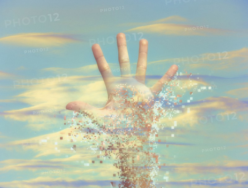 Pixelated hand dissolving in sky