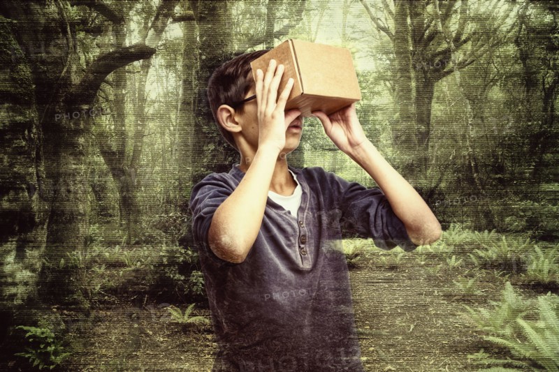 Mixed race boy peering in box in forest