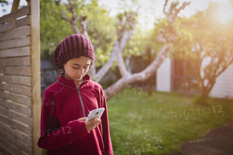 Mixed race girl using cell phone in backyard