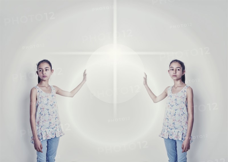 Mirror image of mixed race girl reaching for light