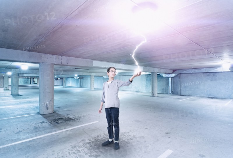 Mixed race boy holding lightning in parking lot