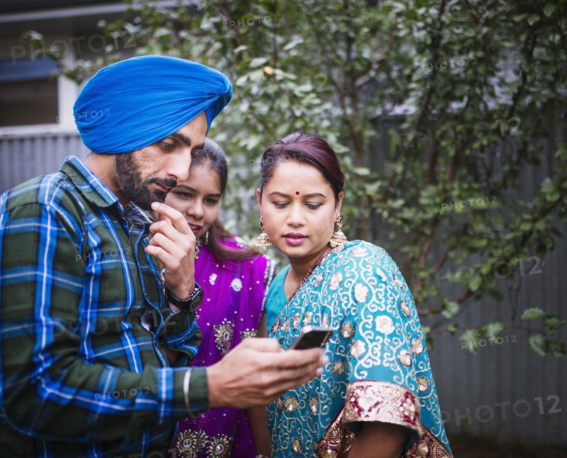 Family in traditional Indian clothing using cell phone