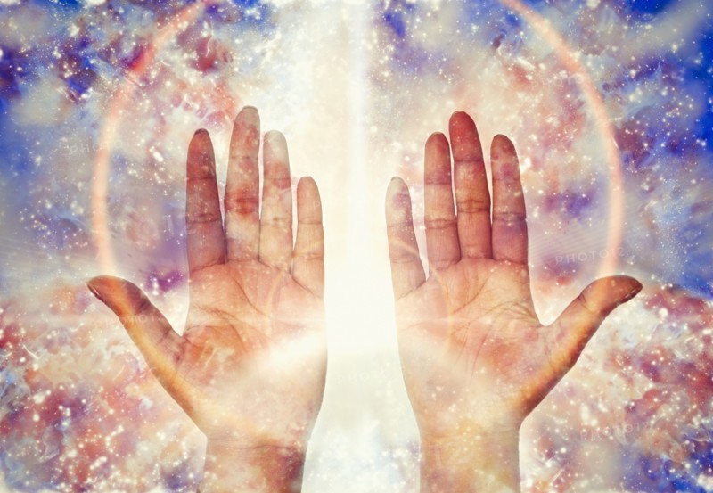 Close up of light glowing from hands of mixed race woman