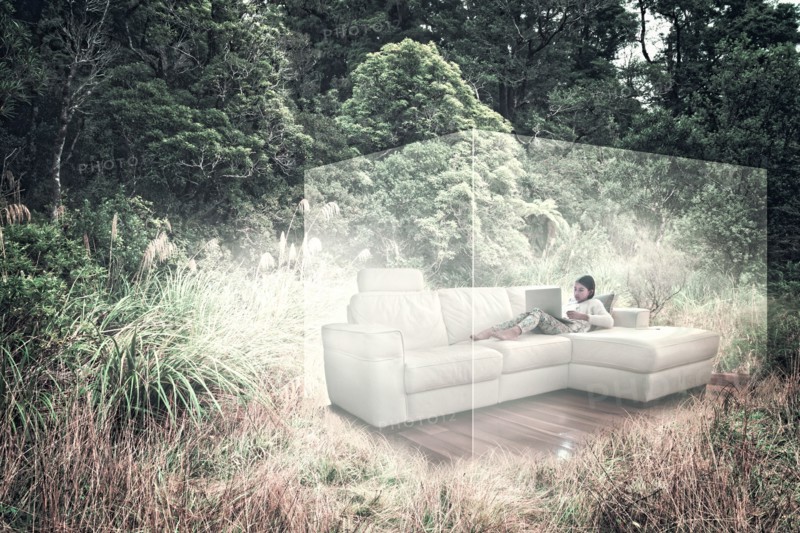 Mixed Race girl using laptop on sofa in virtual cube