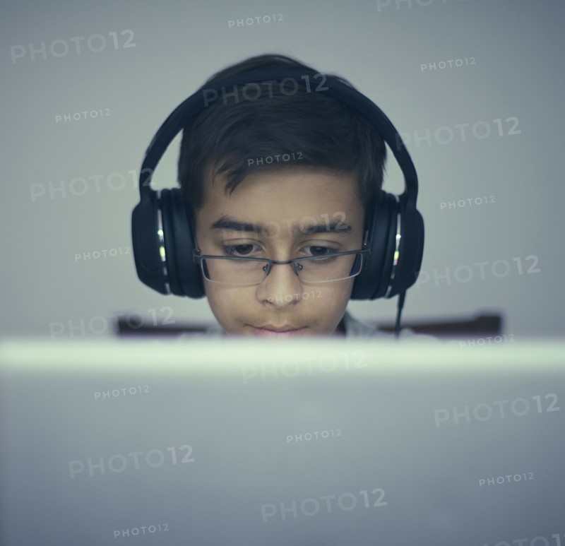Mixed Race boy listening to laptop with headphones