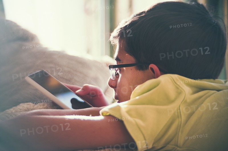 Mixed Race boy texting on cell phone near window