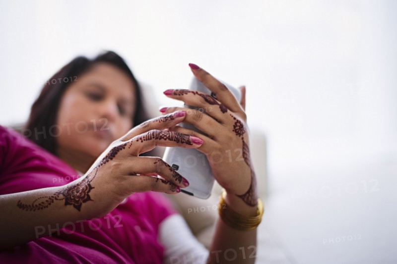 Woman with henna tattoos on hands texting on cell phone