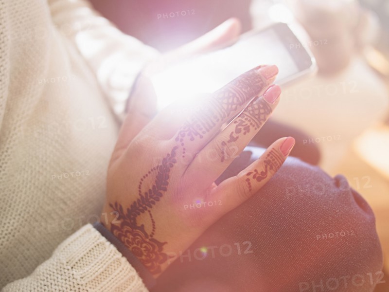 Woman with henna tattoos on hands texting on cell phone