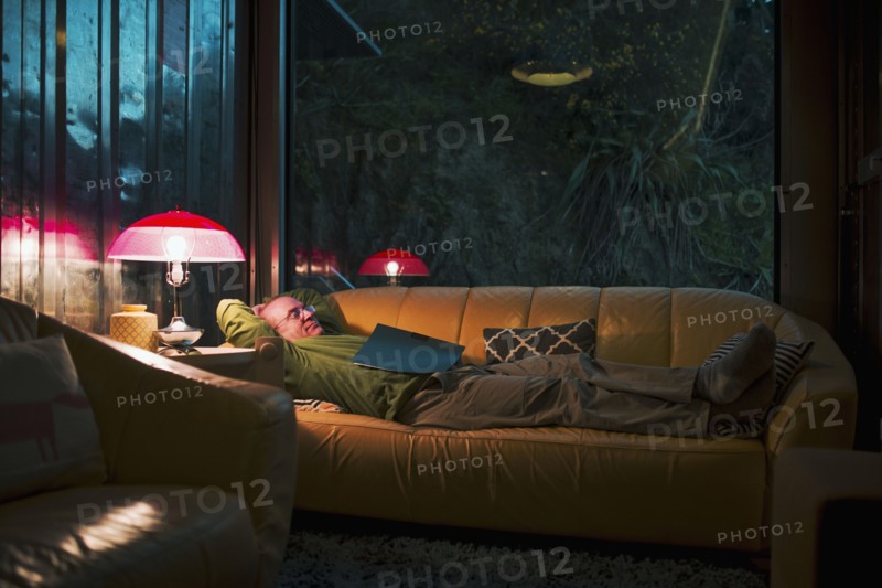 Caucasian man relaxing on sofa with book