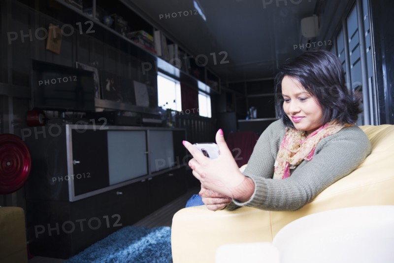 Woman sitting on sofa texting on cell phone