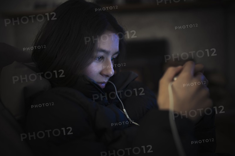 Mixed Race girl listening to cell phone with earbuds