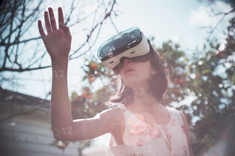 Mixed Race girl using virtual reality goggles outdoors