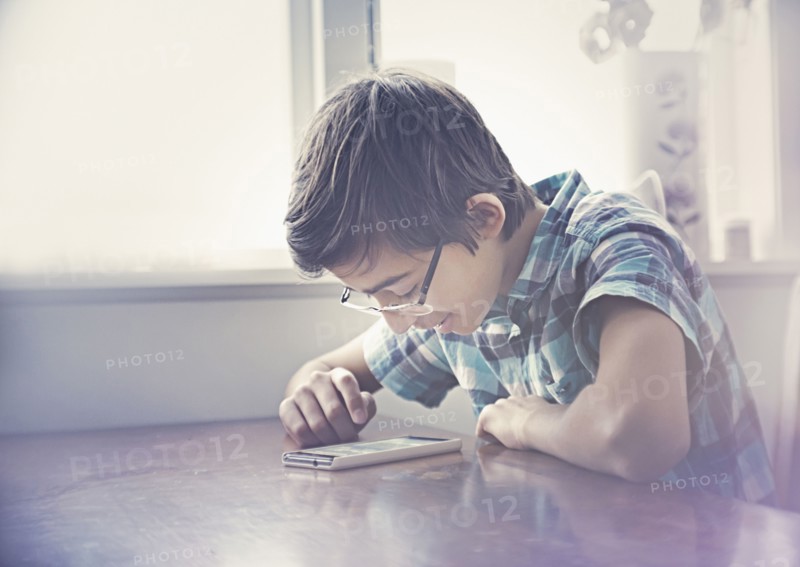 Smiling Mixed Race boy texting on cell phone