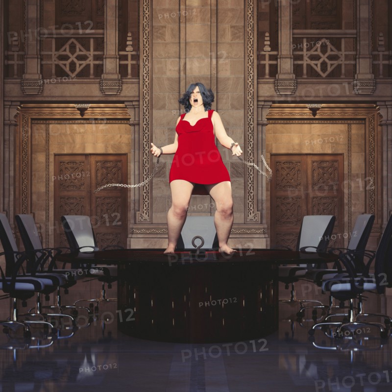 Woman standing on conference table breaking shackles