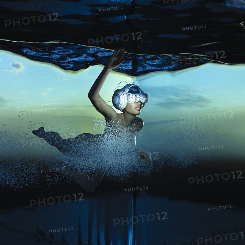 Woman swimming underwater wearing virtual reality helmet