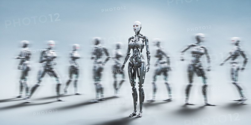 Robot woman standing still near walking robots