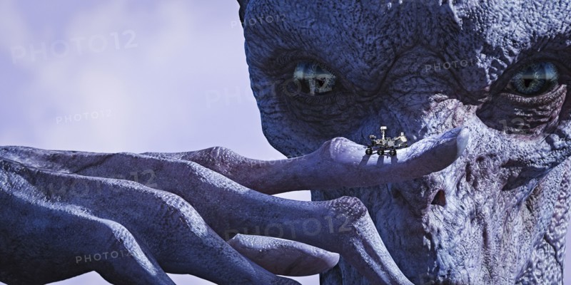 Alien examining tiny vehicle on finger