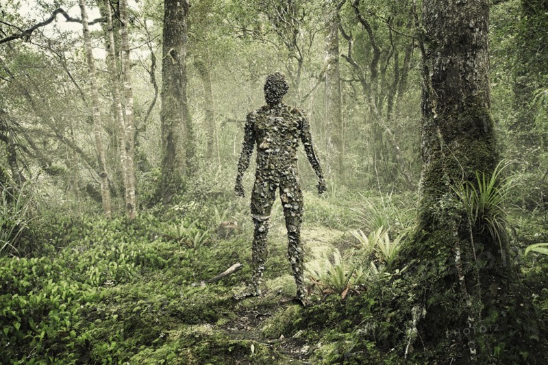 Man covered with rocks in forest