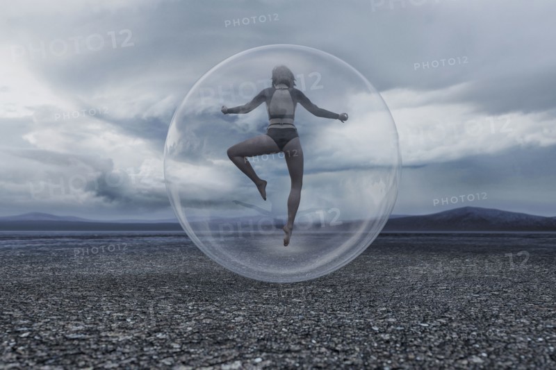 Woman floating in sphere in remote landscape