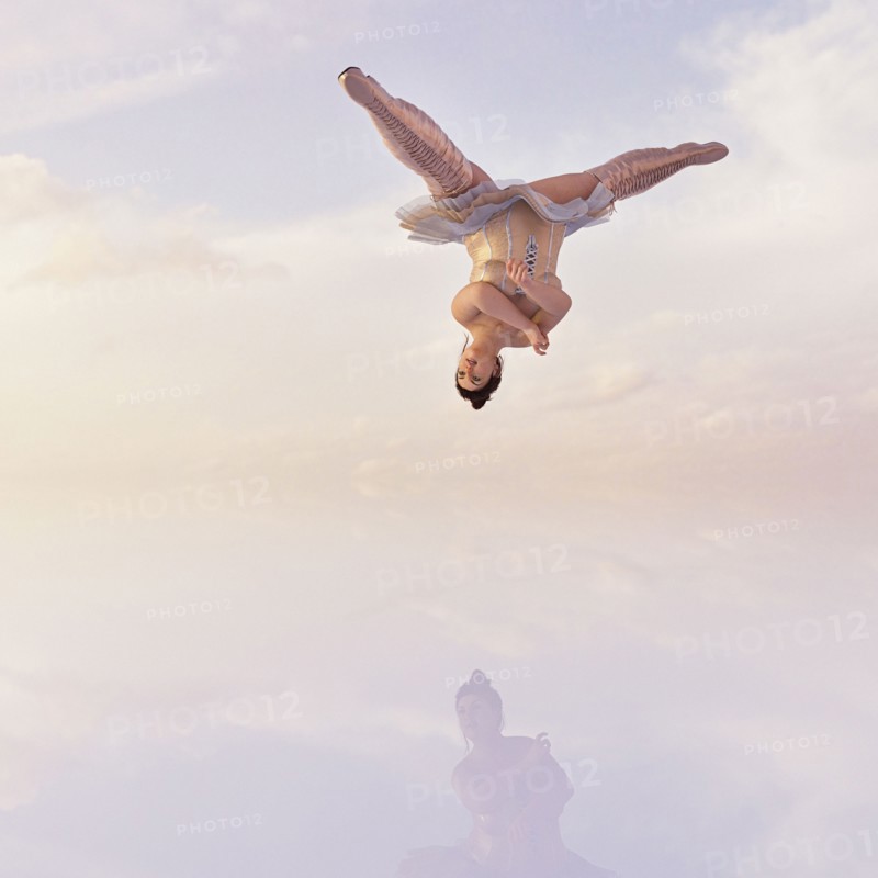 Woman wearing corset and boots upside-down in clouds